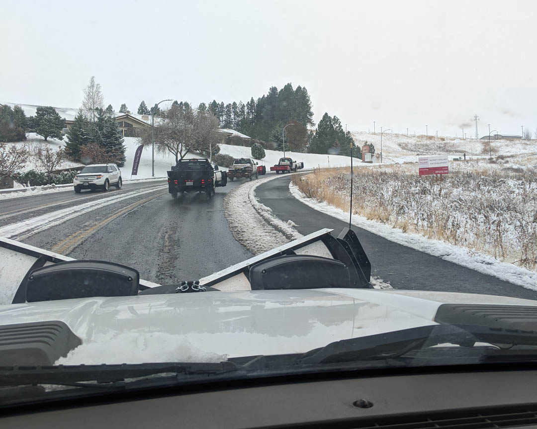 Line of snow plow pickups driving on the road