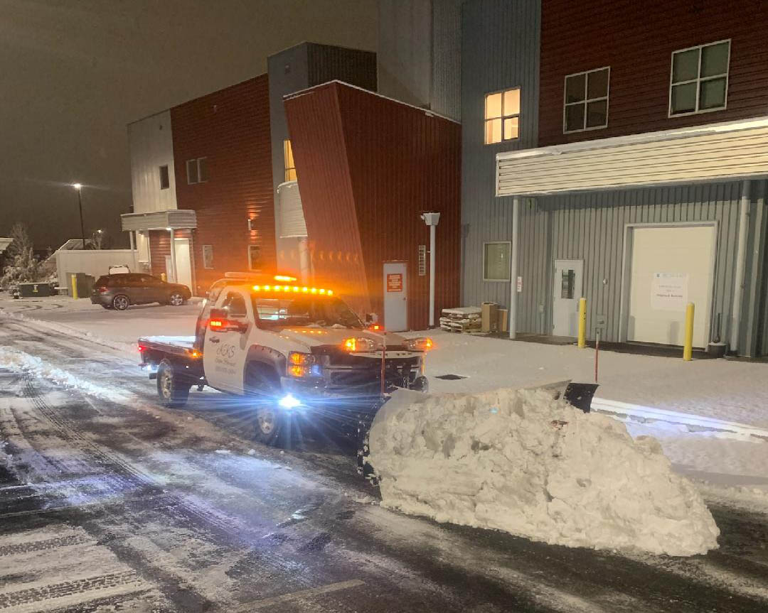 Snow plow pickup with pile of snow in front of blade.