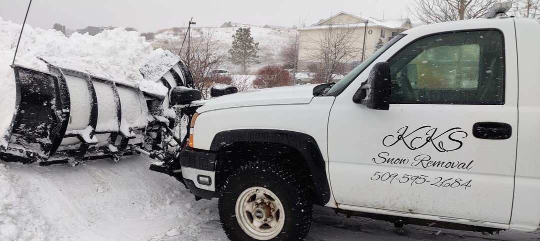 Snow plow pickup with pile of snow in front of blade.